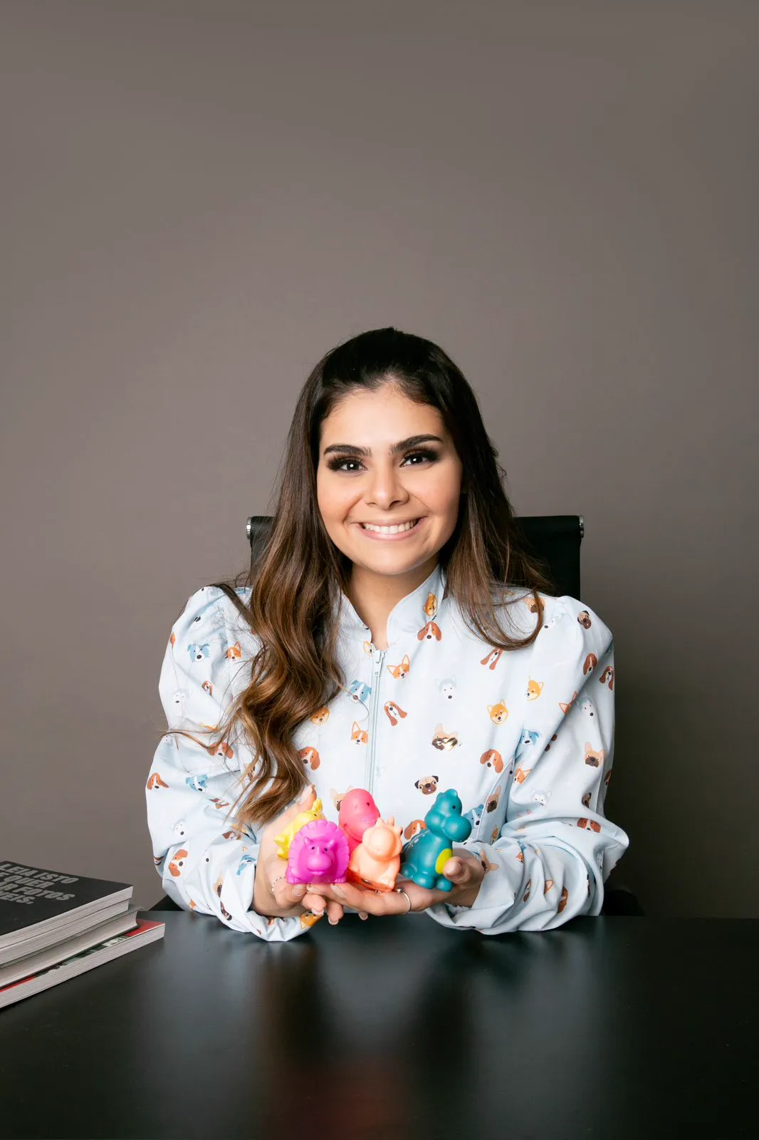 A Dra. Desirée sorrindo, com dinossauros de brinquedo nas mãos.